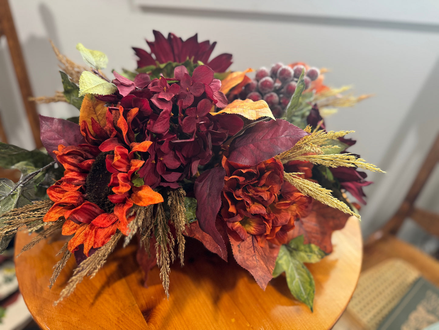 Autumn-themed floral arrangement on a wooden table with a neutral background