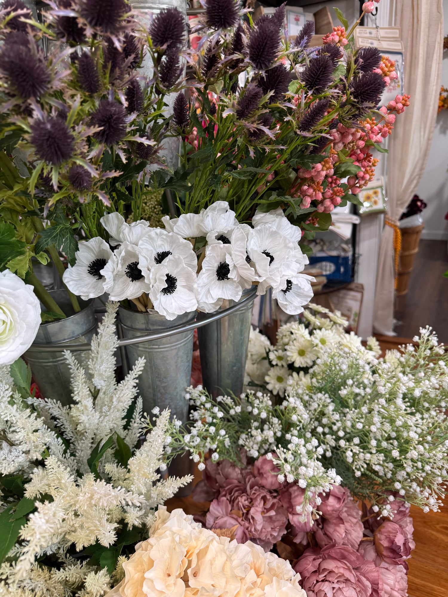 A display of artificial flowers such as Anemone, Peony, Astilbe, Hydrangea, Thistle, and Baby's Breath