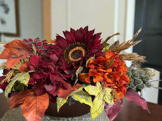 Autumn-themed faux flower arrangement with burgundy red and rust orange flowers in a low oval dish. Amazing for console or entryway table or dining table. 